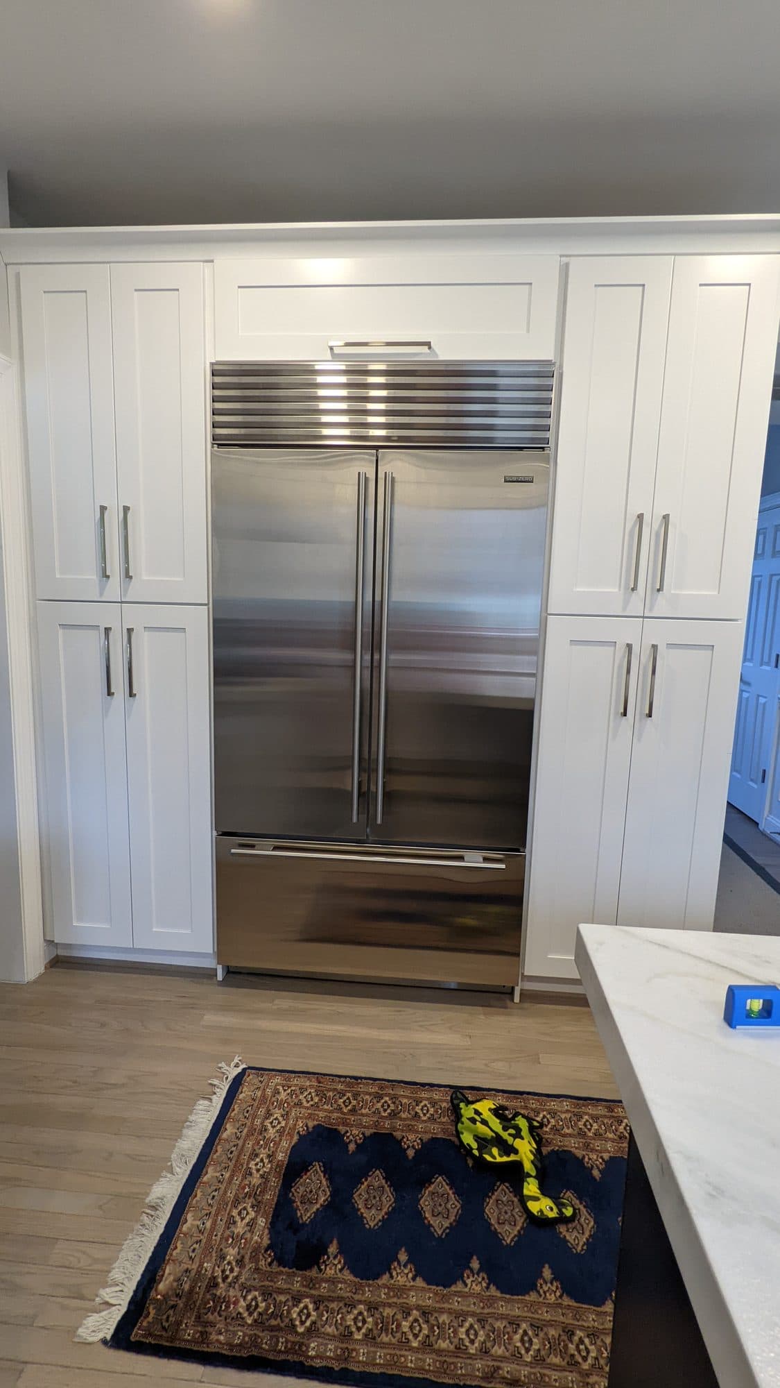 Built-in stainless refrigerator flanked by floor-to-ceiling white pantry cabinetry