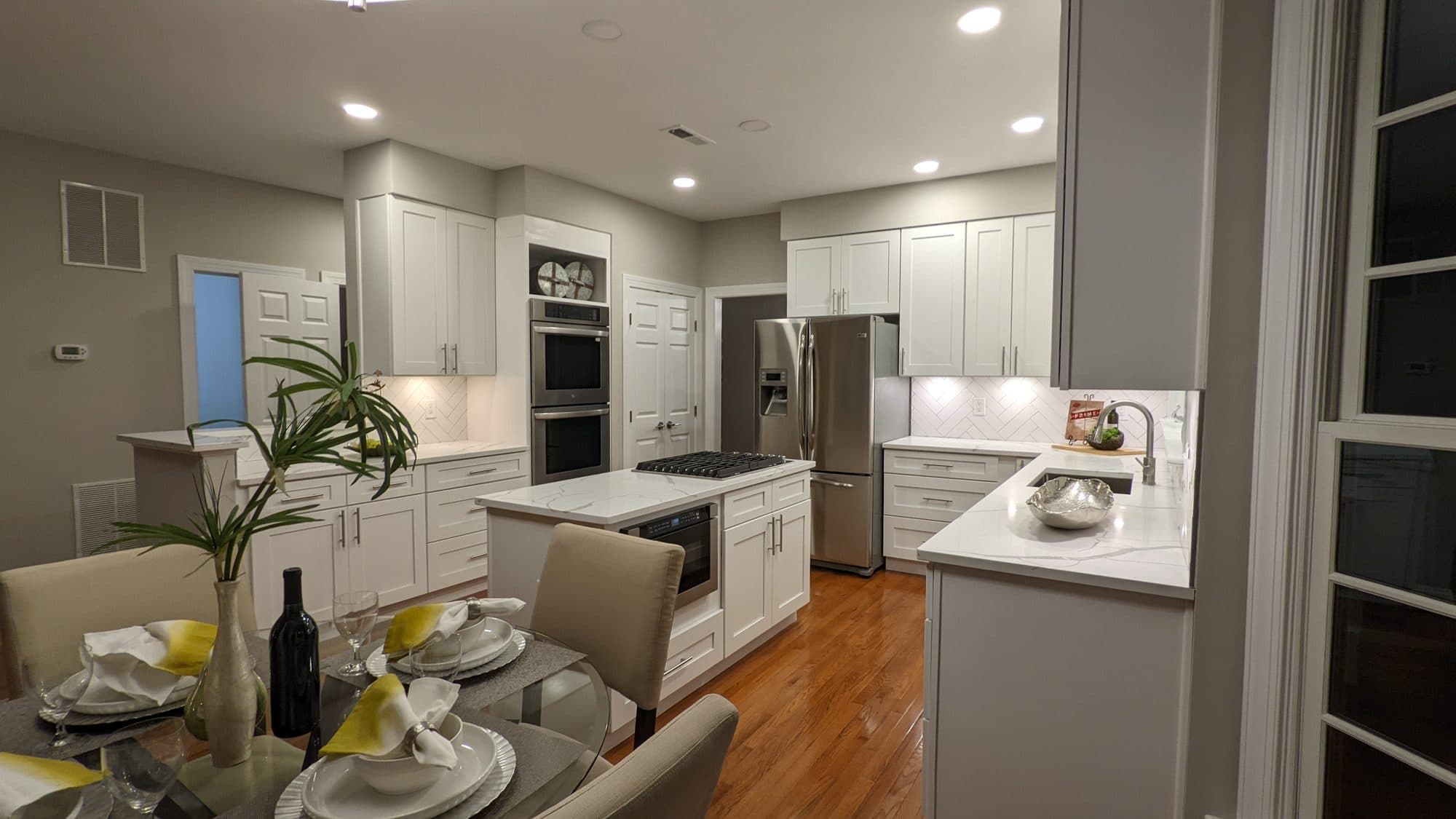 Kitchen with herringbone tile backsplash, stacked wall ovens, and an eat-in dining area